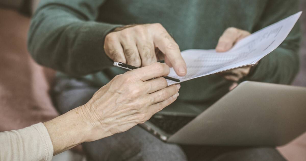 Older adult reviewing an estate planning document with an advisor over a laptop
