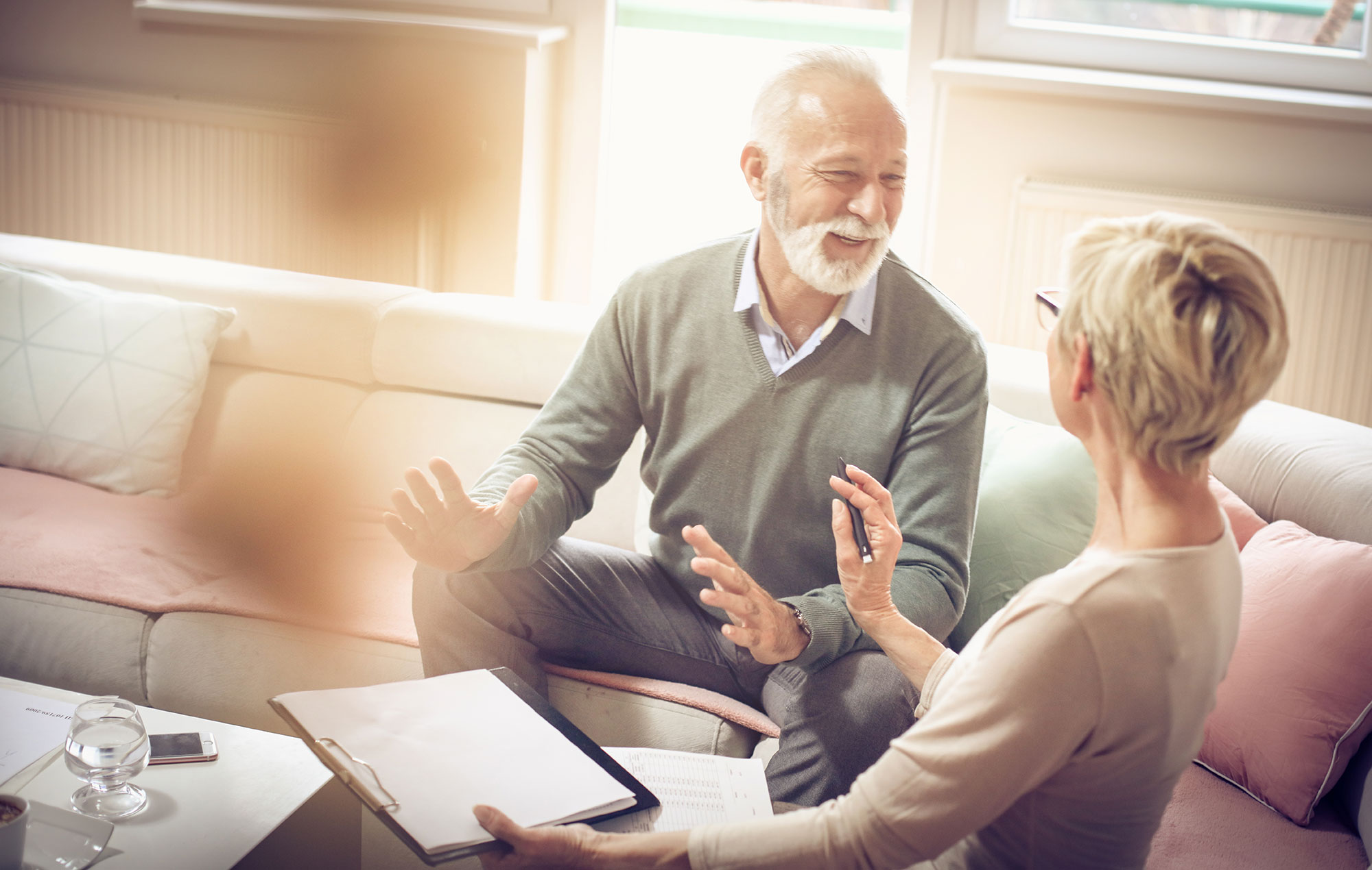 Older couple talking with an adviser over documents on a sofa