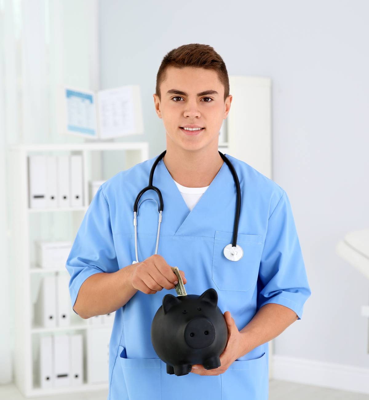 5 Financial Mistakes Physicians Make (And How to Help Avoid Them) 1 Young man in scrubs with a stethoscope holding a black piggy bank
